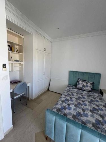 a bedroom with a blue bed and a desk at Maison cosy et moderne in Dar Tahar Zaouch