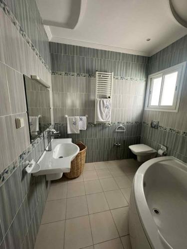 a bathroom with a sink and a tub and a toilet at Maison cosy et moderne in Dar Tahar Zaouch