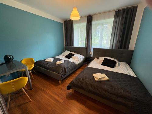 a bedroom with two beds and a table and chairs at Great Polonia Beach & Molo in Puck