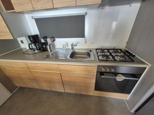 une petite cuisine avec un évier et une cuisinière dans l'établissement Mobil-home camping 5 etoiles, à Valras-Plage