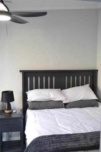 a bed with white sheets and pillows and a ceiling fan at The Sparrow Room in East London