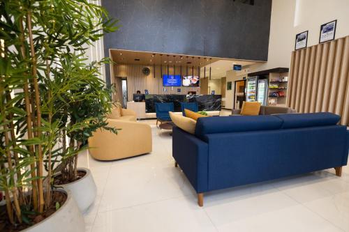 un hall avec des canapés bleus, des chaises et des plantes dans l'établissement Rota 44 Hotel, à Goiânia
