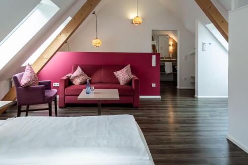 a living room with a red couch and a table at Hotel Hofgut Sternen - Ravennaschlucht in Breitnau