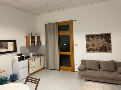 Una sala de estar con un sofá y una cocina. en Vlnena Apartmans, en Brno