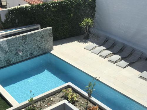 a swimming pool with lounge chairs next to a patio at Quinta Azul, boutique homestay in Foz do Arelho