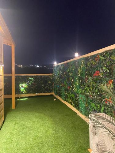 a balcony with a green garden at night at كوخ خزامى الباحة in Al Baha