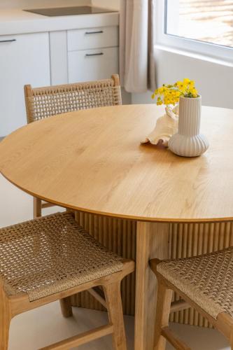 a wooden table with two chairs and a vase with flowers at Sorobon Bay Hotel in Kralendijk