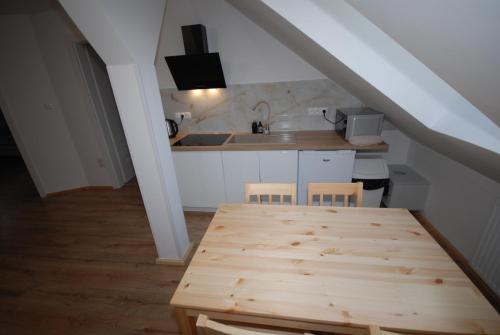 a kitchen with a wooden table and a kitchen under a stairs at Noclegi Dywity in Dywity