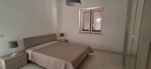 a bedroom with a bed and a window at Le Pigne casa vacanze. in Pollica