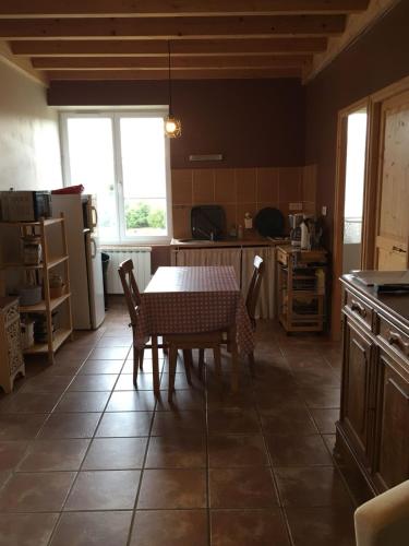 une cuisine avec une table et des chaises dans une cuisine dans l'établissement La Buissonnière, à Saint-Vincent
