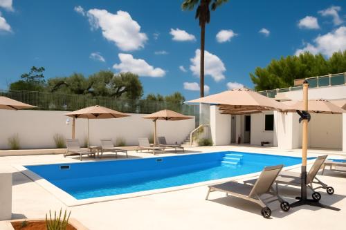 a swimming pool with chairs and umbrellas at Castellinaria Holiday in Castellana Grotte