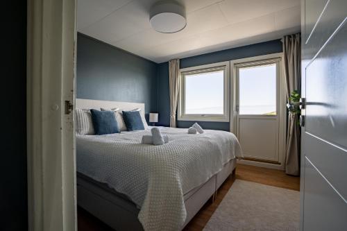 a bedroom with a bed with blue walls and a window at Reinefjorden Family House in Reine