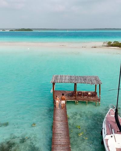 two people standing on a dock in the water at Nómadas Bacalar- Departamentos - in Bacalar