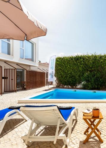 a white chair and an umbrella next to a swimming pool at Santa Cruz Dive House - PADI Centre in Santa Cruz