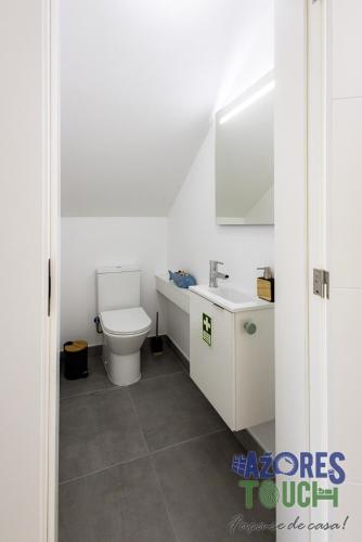 a white bathroom with a toilet and a sink at Casa Menino do Mar in Porto Judeu