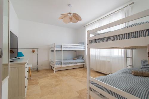 ein Schlafzimmer mit zwei Etagenbetten und einem Schreibtisch in der Unterkunft Somptueuse villa piscine terrain de pétanque à 10 min de Sète in Frontignan