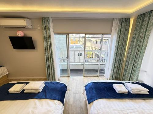 two beds in a room with a view of a balcony at 浅草駅徒歩8分 浅草寺すぐそばの仲見世散策ステイ DqcSoY in Tokyo