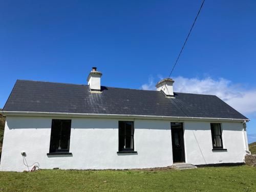 a white house with a black roof at Glenurla Valley Cottage in Ballycastle