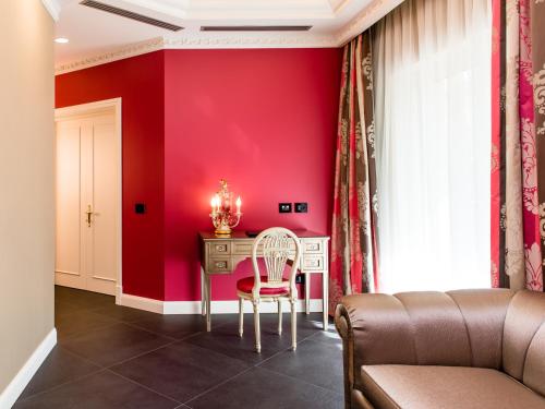 a living room with red walls and a table with a chair at Hotel Villa e Palazzo Aminta in Stresa