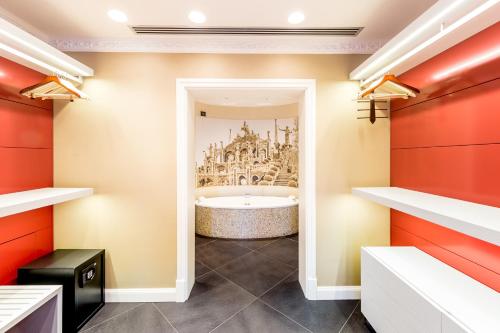 a bathroom with a tub and a red wall at Hotel Villa e Palazzo Aminta in Stresa