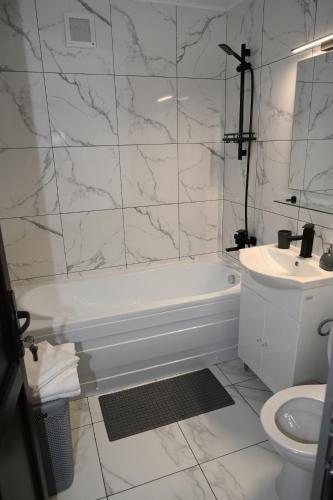 a white bathroom with a tub and a sink at Luxury Home in Cîmpulung