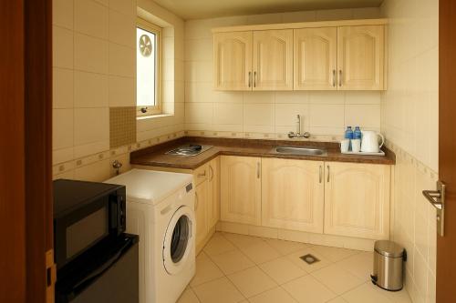 a kitchen with a washing machine and a microwave at Dream Palace Hotel in Ajman 