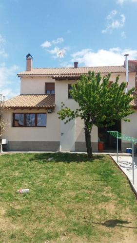 a white house with a tree in the yard at Albergue Vive tu Camino in Reliegos