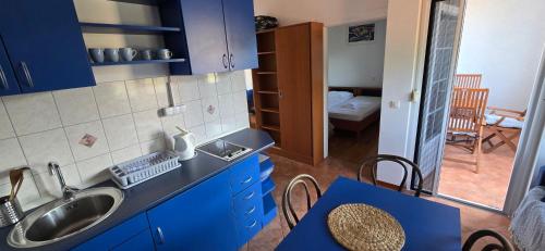 a kitchen with blue cabinets and a sink and a table at Apartments Villa Andreja in Starigrad