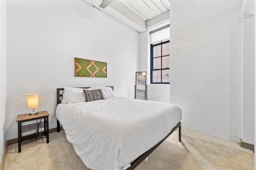 Un dormitorio blanco con una cama y una mesita de noche. en Loft on Superior l DT Cleveland l Parking l Café, en Cleveland