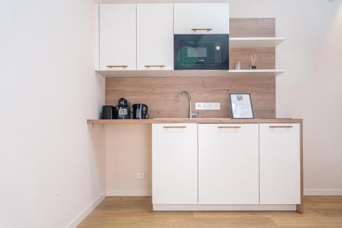 une cuisine avec des armoires blanches et un évier dans l'établissement Le Toit d'Azur, à Nice