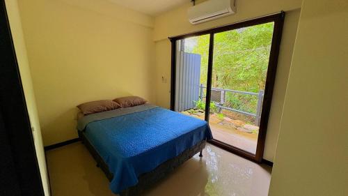 a bedroom with a bed and a large window at Stay by Iguana in Quepos
