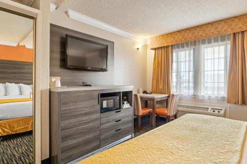 a hotel room with a bed and a tv and a table at Arbor Inn Monterey in Monterey