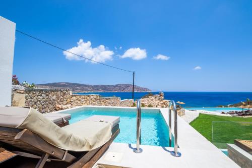 a villa with a swimming pool with a view of the ocean at Aegean Village Beachfront Resort in Amoopi