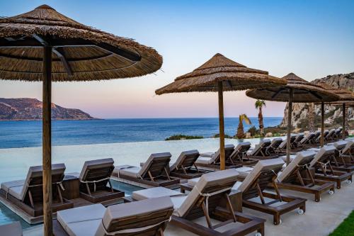 a row of chairs and umbrellas on the beach at Aegean Village Beachfront Resort in Amoopi