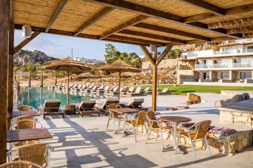 a patio with tables and chairs and a pool at Aegean Village Beachfront Resort in Amoopi