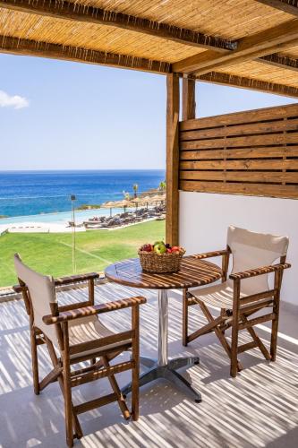 a table and two chairs on a deck with the ocean at Aegean Village Beachfront Resort in Amoopi