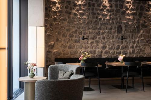a dining room with tables and chairs and a wall with a stone wall at Eisenhut Boutique Hotel in Bolzano