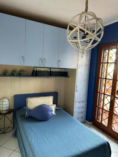 a bedroom with a blue bed and a chandelier at La Casa di SASI in Sabaudia