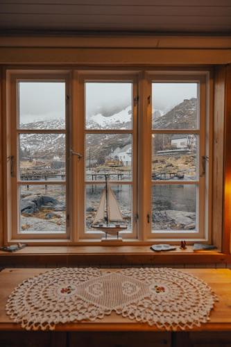 a window with a toy sailboat in a room at Arctic Fishermans Lodge- SAUNA included in Moskenes