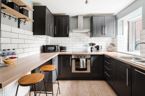 a kitchen with black cabinets and wooden counter tops at Modern 2 Bedroom House with Parking in Manchester