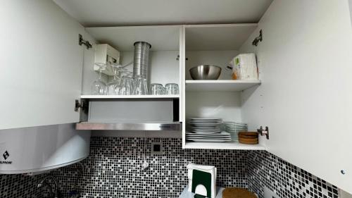 a kitchen with white cabinets with plates and dishes at THE Estoril Studio in Estoril