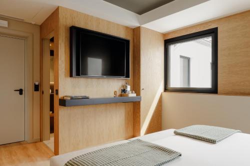 a bedroom with a flat screen tv and a bed at Porto River Soul Hotel in Vila Nova de Gaia