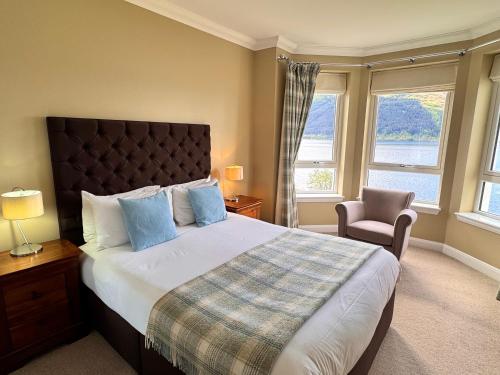 a bedroom with a large bed and a chair at Allt Nan Ros Apartments fort william in Onich