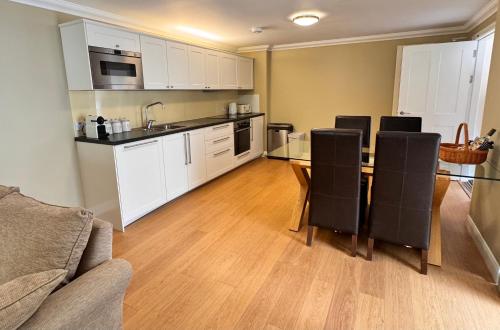 a kitchen with white cabinets and a table and chairs at Allt Nan Ros Apartments fort william in Onich