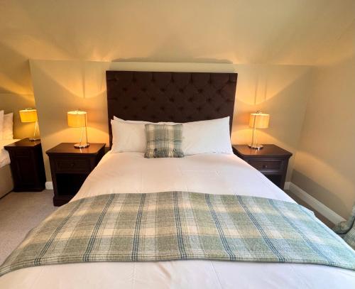a bedroom with a large bed with two lamps at Allt Nan Ros Apartments fort william in Onich