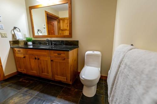 a bathroom with a toilet and a sink and a mirror at Creekside 2-Bedroom Condo in Canmore