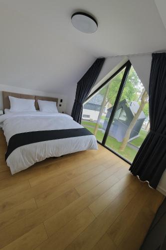 a bedroom with a large bed and a large window at Treehouses in Skorochów