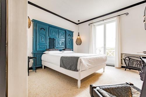 una camera da letto con un letto con testiera blu di Hotel de Charme Le Sud Bretagne a Pornichet