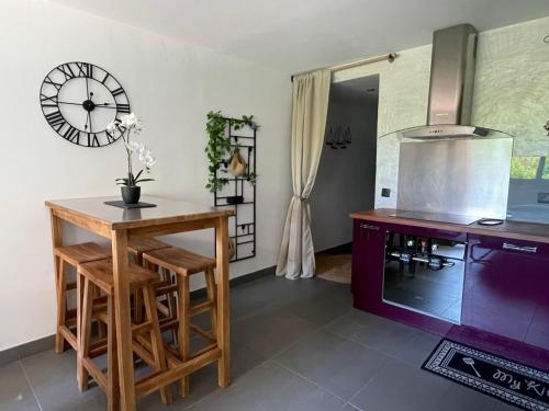 une cuisine avec une table et une horloge au mur dans l'établissement Oasis Littorale, à La Ciotat