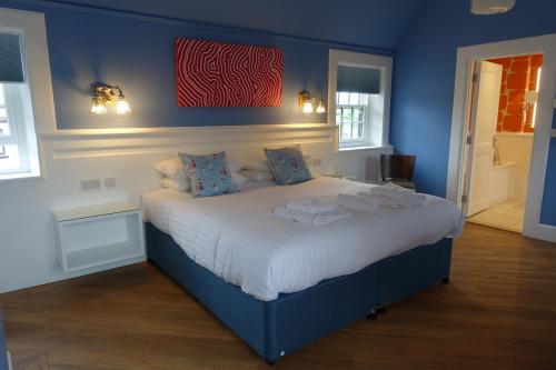 a blue bedroom with a large bed with blue walls at One Holyrood Hotel & Cafe in Newport